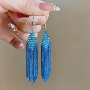 Close-up of elegant blue beaded earrings featuring a diamond shape and long fringe tassels