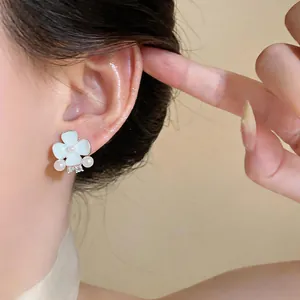 Close-up detail of an elegant floral stud earring with white oil petals and pearls