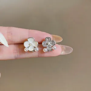 Close-up of sweet asymmetric pearl flower earrings with enamel and pave crystals