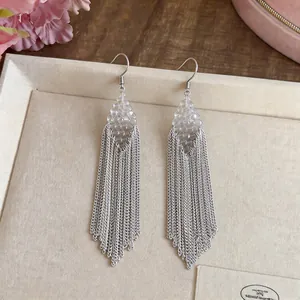 Detailed view of silver metal chain tassel earrings with clear beaded diamond-shaped top