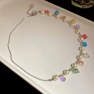 Close-up of asymmetrical necklace with white pearls and colorful crystal beads on a tray
