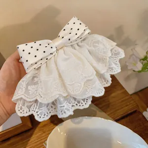 Detailed view of the intricate white lace embroidery and polka dot bow hair clip