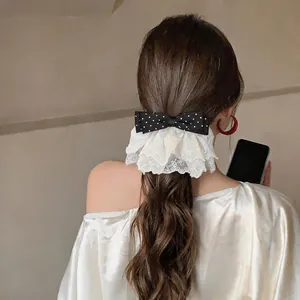 Detailed close-up of a stylish polka dot bow hair clip with elegant lace ruffles on wavy hair