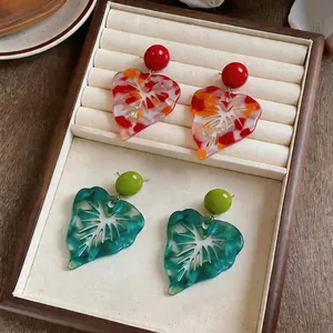 Exaggerated resin leaf earrings with colorful marbleized pattern and round stud tops