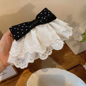 Macro detail shot of a white lace hair clip with a stylish black polka dot bow.