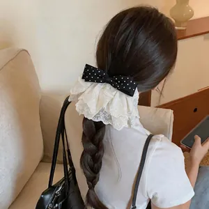 Detailed back view of a woman wearing a black polka dot bow hair clip with white lace trim.