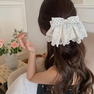 Rear view of a white lace polka dot bow hair clip styled in long wavy brown hair