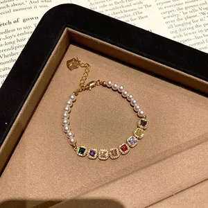 Dettaglio macro di bracciale di perle con zirconi colorati in una scatola regalo.