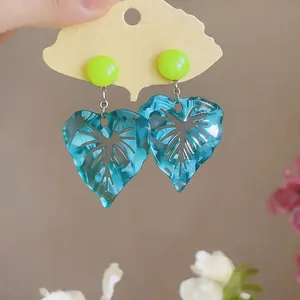 Detail view of resin leaf earrings with marbled teal texture and lime green studs
