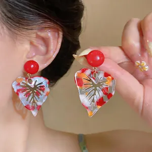 Close-up of colorful marbled resin leaf earrings with gold metal vein detail.