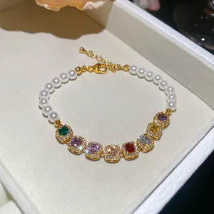 Primo piano di braccialetto di perle con zirconi colorati e gemme quadrate geometriche