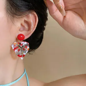 Close-up view of large resin leaf earrings featuring a vibrant colorful variegated pattern