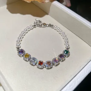 Dettaglio di un elegante bracciale di perle con vivaci zirconi quadrati colorati