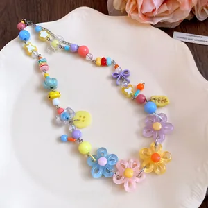 Detailed view of colorful dopamine style beaded necklace with daisy floral charms on a tray