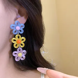 Close-up detail of colorful dopamine style triple layer daisy drop earrings worn on ear