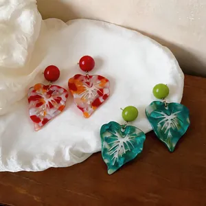 Close-up of marbled resin leaf earrings with colorful patterns and hollow design