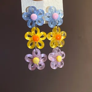 Detailed macro view of colorful three-tier acrylic daisy drop earrings in dopamine style