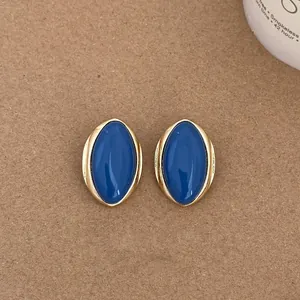 Close-up of vintage oval stud earrings featuring a deep blue inlay and polished gold-toned frame