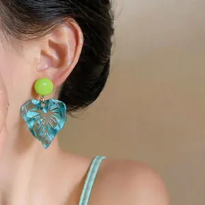 Close-up view of a stylish resin leaf drop earring featuring vibrant colors worn on the ear
