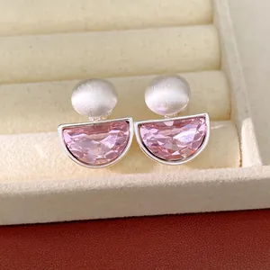 Dettaglio di eleganti orecchini a clip semicircolari in cristallo rosa e argento opaco.