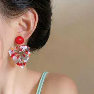 Close-up of vibrant colorful resin leaf earrings with gold vein detail on a model.