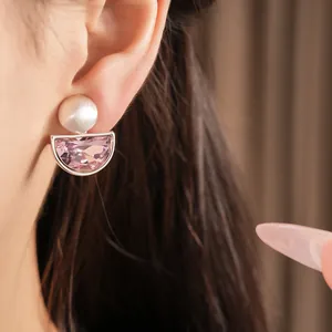 Dettaglio ravvicinato di eleganti orecchini a clip a semicerchio in cristallo rosa su orecchio