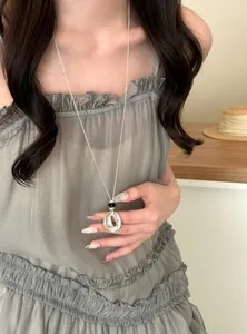 Model wearing a resin pleated round pendant long necklace for a minimalist chic style