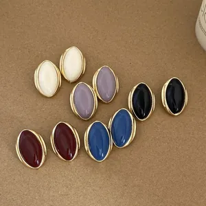 Detail view of multiple vintage oval stud earrings in five elegant colors on kraft paper