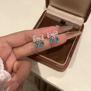 Close-up of elegant bowknot earrings with heart-shaped blue zircon stones