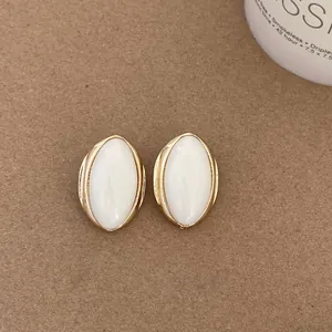 Close-up detail of vintage oval earrings with white centers and gold textured frames