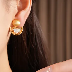 Dettaglio di eleganti orecchini a semicerchio in oro con cristalli color champagne