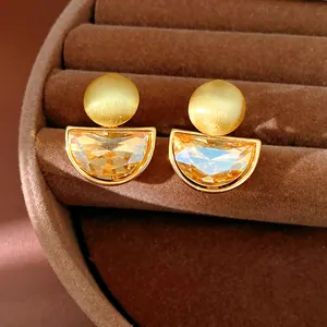 Dettaglio di orecchini a clip semicircolari in oro opaco con pietre ambrate sfaccettate