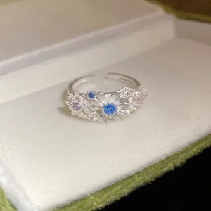 Elegant silver daisy flower ring with blue gemstones displayed in a gift box.