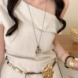 Minimalist silver irregular ring titanium steel long necklace shown on a beige linen dress
