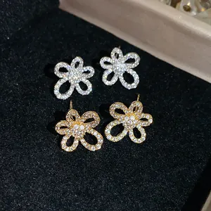 Detail view of flower-shaped stud earrings with 18k gold plating and sparkling zircon stones.