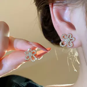 Macro detail of gold-plated flower stud earrings inlaid with sparkling zircons