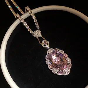Close-up of elegant oval pink gemstone pendant necklace with shimmering crystals.