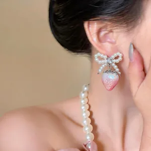 Detailed view of French-style strawberry earrings with pearl bow and zircon accents.