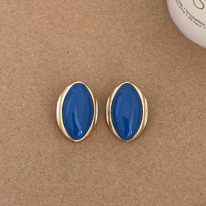 Close-up of vintage oval stud earrings with deep blue enamel and gold-toned borders.