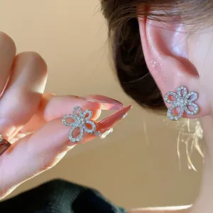 Close-up of zircon-paved flower stud earrings with elegant hollow petal design