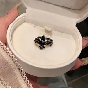 Elegant gothic black zircon cross fleur-de-lis ring displayed in a white jewelry gift box