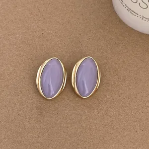 Close-up view of elegant vintage oval stud earrings with lavender stone and gold frame