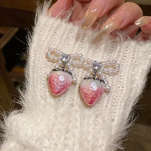 Close-up of sweet strawberry earrings with pearl bows and shimmering zircons