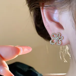 Detailed view of an 18k gold-plated zirconia flower earring worn on a model's ear