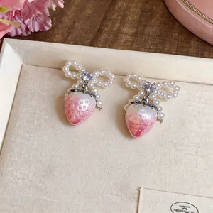 Close-up detail of sweet strawberry earrings featuring pearl bows and sparkling zircon