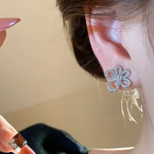 Close-up view of sparkling zircon flower stud earring worn on ear, 18k gold plated
