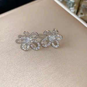 Close-up detail of 18k gold plated flower stud earrings with shimmering cubic zirconia.
