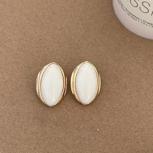Close-up of vintage-style oval stud earrings with white inlay and gold frame