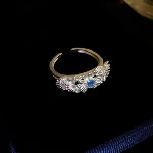 Detailed macro view of a silver daisy flower ring with colorful stones on black velvet.
