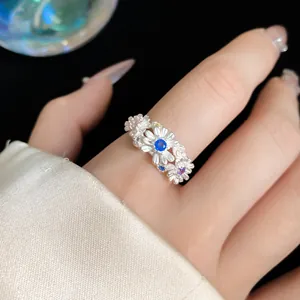 Detailed macro view of a silver daisy flower ring with colorful stones on a finger